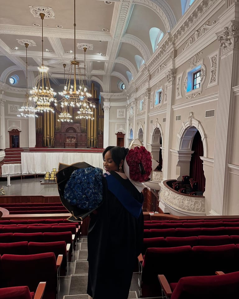 A graduate carrying blue and red glitter rose bouquets
